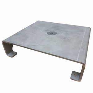 May include: A silver metal base with a round hole in the center. The base has a rectangular shape with rounded edges and two small rectangular tabs on the sides.