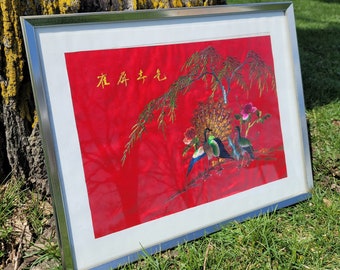 May include: A framed embroidered artwork featuring a red background with a tree branch and three birds. The birds are green, blue, and yellow. The Chinese characters "永年吉庆" are embroidered in gold thread on the red background.