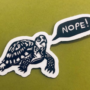 May include: A black and white sticker of a turtle with a speech bubble that says "NOPE!"