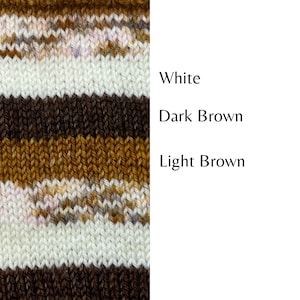 以下が含まれることがあります： 白、濃い茶色、薄い茶色の水平なストライプが入ったニット生地です。