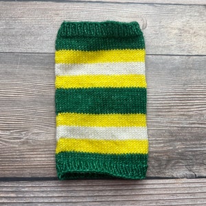 May include: A knitted cozy in green, yellow, and white stripes. The cozy is a tube shape, designed to fit around a beverage container. The top and bottom edges are a solid green color.