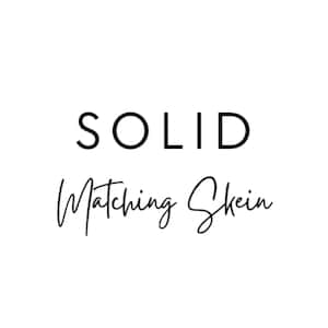 May include: White background with the words "SOLID" in a bold, sans-serif font above the words "Matching Skein" in a cursive font. The text is black.