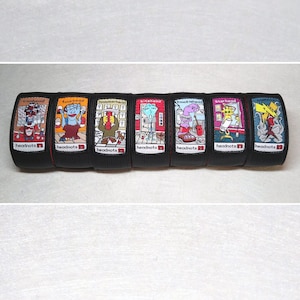 May include: Seven black wristbands with colorful cartoon characters and the text "headnots" on each. The characters are wearing different outfits and have different expressions.