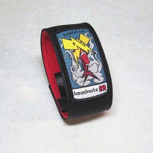 May include: Black wristband with red lining and a colorful patch featuring a lightning bolt graphic and the text "zaphead" and "headnots n".