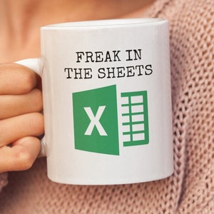 Puede incluir: Taza de caf&eacute; blanca con el texto "Freak in the sheets" y un logotipo verde de Microsoft Excel.