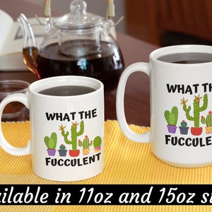 May include: Two white ceramic mugs with black text and colorful cactus illustrations. The text on the mugs reads "What the Fuccolent". The mugs are available in 11oz and 15oz sizes.