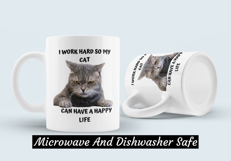 May include: White ceramic mug featuring a grey cat image and the text "I work hard so my cat can have a happy life". The mug is microwave and dishwasher safe.