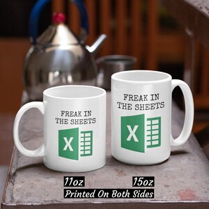 Puede incluir: Dos tazas de cer&aacute;mica blanca con un logotipo de Microsoft Excel verde y el texto "Freak in the sheets". Las tazas son de 11oz y 15oz y est&aacute;n impresas en ambos lados.