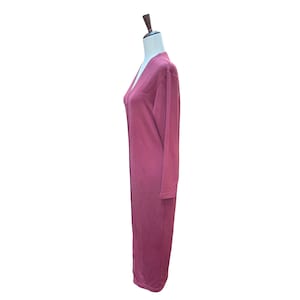 May include: A long, burgundy-colored cardigan dress with long sleeves. The dress has a V-neckline and a relaxed fit. The garment is displayed on a mannequin against a white background. The dress appears to be made of a soft, comfortable material.