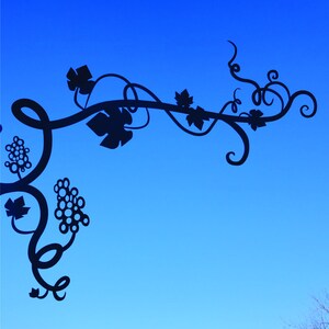 May include: A black silhouette of a vine with leaves and grapes against a bright blue sky.