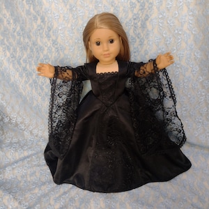 Puede incluir: Un vestido de muñeca de satén negro con mangas de encaje y un escote de corazón. El vestido está diseñado para una muñeca de tamaño similar a una muñeca American Girl.