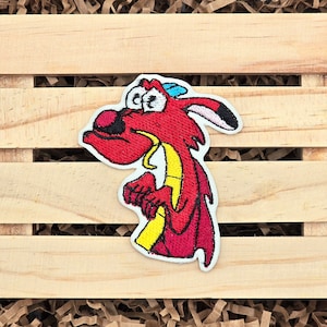 May include: Embroidered patch featuring a red dragon with a yellow belly and a blue hat. The dragon has large, expressive eyes and is set against a white background. The patch is likely for clothing or accessories.