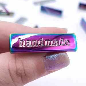 May include: A rainbow iridescent metal tag with the word "handmade" embossed in silver lettering.