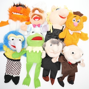 May include: A set of nine colorful hand puppets featuring characters from the Muppets. The puppets include Miss Piggy, Kermit the Frog, Animal, Fozzie Bear, Gonzo, Scooter, and Statler and Waldorf.