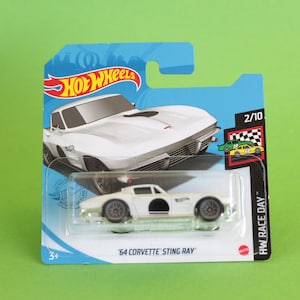 May include: A white 1964 Corvette Sting Ray Hot Wheels car in a blue and white package. The car is a 2/10 in the HW Race Day series. The package has the Hot Wheels logo and the words "HW Race Day".