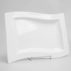 Puede incluir: Un plato de servir de cerámica blanca con un borde ondulado. El plato está vacío y está sobre una superficie blanca.