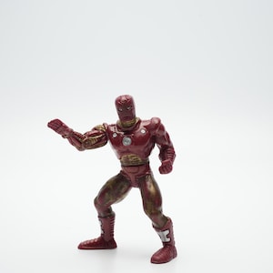 Pode incluir: Figura de a&ccedil;&atilde;o de pl&aacute;stico vermelha e dourada do Homem de Ferro em pose de luta. A figura tem um acabamento de pintura met&aacute;lica vermelha e dourada.
