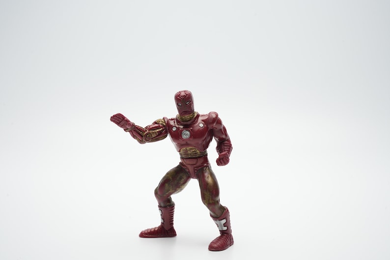 Pode incluir: Figura de a&ccedil;&atilde;o de pl&aacute;stico vermelha e dourada do Homem de Ferro em pose de luta. A figura tem um acabamento de pintura met&aacute;lica vermelha e dourada.
