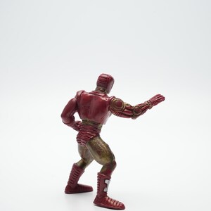 Pode incluir: Uma figura de a&ccedil;&atilde;o vermelha e dourada de um super-her&oacute;i em pose de luta. A figura &eacute; feita de pl&aacute;stico e tem um design detalhado.