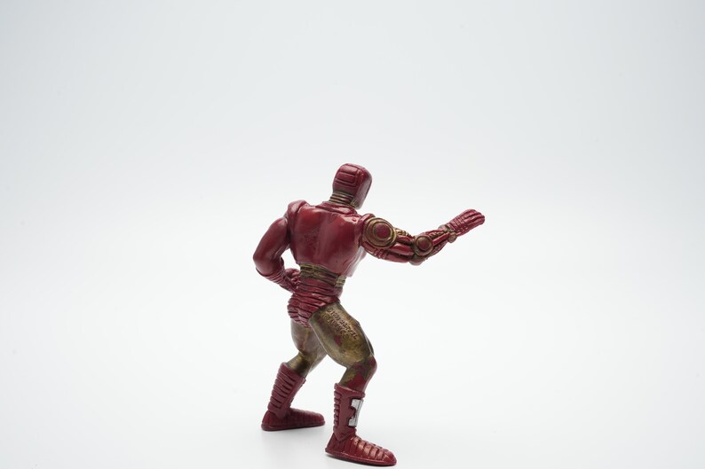 Pode incluir: Uma figura de a&ccedil;&atilde;o vermelha e dourada de um super-her&oacute;i em pose de luta. A figura &eacute; feita de pl&aacute;stico e tem um design detalhado.