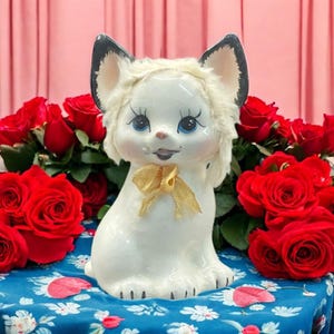 Uroczy japoński zabytkowy porcelanowy skarbonka w kształcie kota z NIEWIELKIMI WADAMI. Z lat 50. XX wieku. Biała ceramiczna figurka ze sztucznym futrem. Malowana ręcznie.