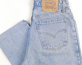 May include: Light blue denim jeans with a brown leather Levi's patch on the back waistband. The patch has the text "Levi Strauss & Co.", "San Francisco, California", "Quality Clothing", and "W 27 L 32".