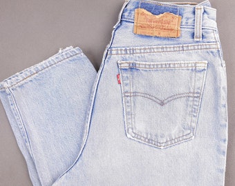 May include: Light blue denim jeans with a brown leather Levi's patch on the back waistband. The jeans have a high waist and a straight leg.