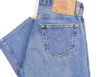 Puede incluir: Un par de pantalones vaqueros azules de mezclilla con un parche de cuero marrón en el bolsillo trasero. El parche tiene el logotipo de Levi's y el texto "501®" y "W31 L32".