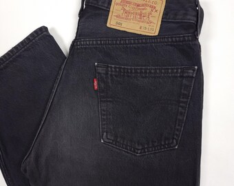 Peut inclure: Gros plan sur un jean en denim noir avec une conception classique à cinq poches. Le jean présente une étiquette rouge Levi Strauss & Co. sur la poche arrière et une étiquette en cuir marron. Taille de la taille W 30 L 30.
