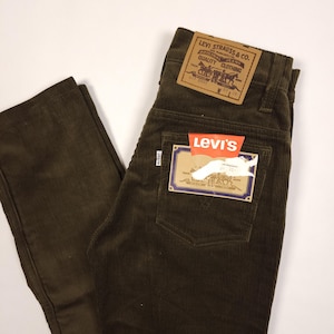 Op de afbeelding: Donker olijfgroene corduroy broek met het Levi's merklabel. De broek heeft een klassiek ontwerp met vijf zakken en een rechte pijp. Het Levi's label is bruin met witte tekst en een afbeelding van paarden.