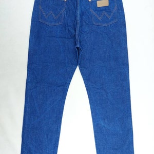 May include: A pair of blue denim jeans with a brown leather patch on the back pocket that says "Wrangler".