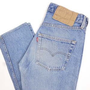 Puede incluir: Vaqueros de mezclilla azul claro con un diseño clásico de cinco bolsillos. Cuenta con un parche de cuero marrón en la parte trasera y una etiqueta roja en el bolsillo trasero. Los vaqueros están ligeramente descoloridos, dándoles un aspecto vintage.