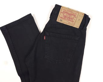 Peut inclure: Jean Levi's 501 noir avec une coupe droite classique. Le jean présente une étiquette rouge Levi's sur la poche arrière et une étiquette marron Levi Strauss & Co. sur la ceinture. La taille est de 68,5 cm et l'entrejambe est de 86,4 cm.