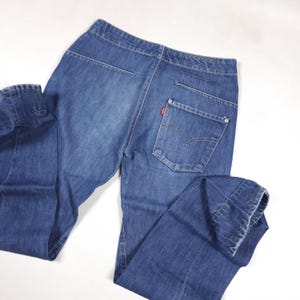 Puede incluir: Vaqueros de mezclilla azules con un diseño clásico de cinco bolsillos. Los vaqueros presentan una etiqueta con el logotipo rojo en el bolsillo trasero y un cierre de botón y cremallera. Los vaqueros están hechos de tela de mezclilla duradera.