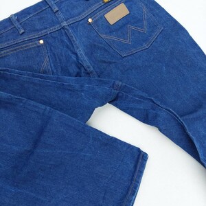 May include: A pair of blue denim jeans with a brown leather patch on the back pocket that says "Wrangler".