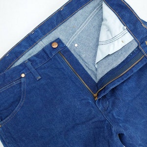 May include: A pair of blue denim jeans with a zip fly and a button fastening. The jeans have a classic five-pocket style.