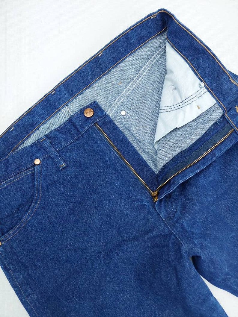 May include: A pair of blue denim jeans with a zip fly and a button fastening. The jeans have a classic five-pocket style.