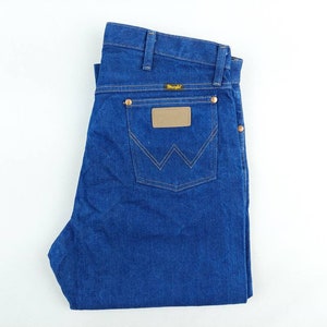 May include: A pair of blue denim jeans with a brown leather patch on the back pocket that says "Wrangler".