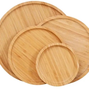 May include: Set of four round wooden serving trays in different sizes. The trays are made of natural bamboo and have a smooth, polished finish.