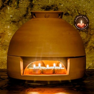 May include: Terracotta candle warmer with a domed lid and a circular opening for tea lights. The warmer is lit with four tea lights inside.