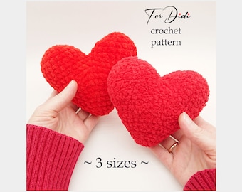 May include: Two red crocheted hearts in three sizes. The hearts are held in the hands of a person wearing a red sweater. The text "For Didi crochet pattern" is above the hearts and the text "~ 3 sizes ~" is below the hearts.