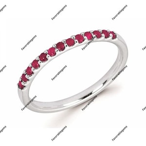 Peut inclure: Une délicate bague en argent avec une rangée de petites pierres rubis rouges brillantes serties dans le métal. La bague est un design simple et élégant.