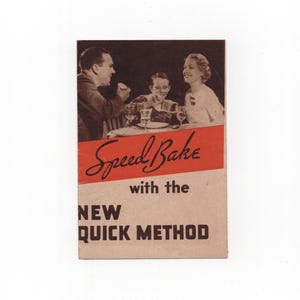 May include: A vintage rectangular paper advertisement featuring a black and white photograph of a family eating at a table. The text reads Speed Bake with the NEW QUICK METHOD in black lettering over a red diagonal stripe and a tan background.