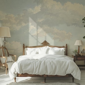 Puede incluir: Una habitación con una cama de madera y ropa de cama blanca. También hay una silla de madera y una mesita de noche. La pared está decorada con un mural de cielo y nubes. Una planta alta en maceta está a la derecha.