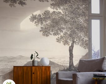 May include: A living room interior with a large wall mural depicting a landscape with a tree in the foreground. The mural is in shades of gray and white. A mid-century modern cabinet with a white lamp sits in front of the mural. A gray armchair sits in the corner of the room.