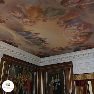 May include: An ornate ceiling painting featuring figures and clouds in shades of beige, peach, and blue. The room has dark wood paneling and framed paintings. The ceiling is decorated with detailed molding.