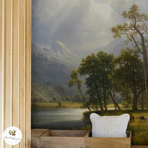May include: A white knitted cushion with a mountain landscape mural in the background. The mural depicts a lake, trees, and mountains.