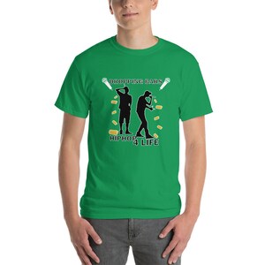 Può includere: Maglietta verde con una silhouette nera di due persone che fanno rap con microfoni. Il testo "Dropping Bars" è sopra le figure e "Hiphop 4 Life" è sotto.