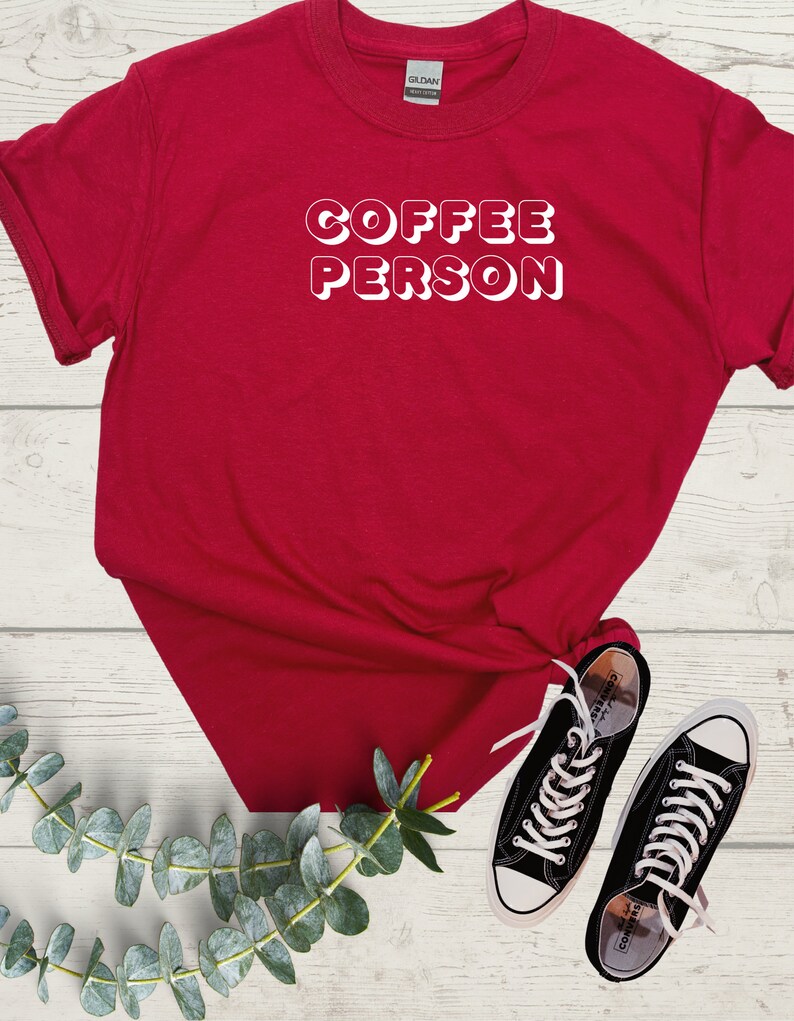 May include: Red t-shirt with white text that reads "COFFEE PERSON" in a retro font.