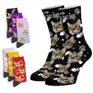 May include: A pair of black socks with a white paw print and fishbone pattern. The socks feature a repeated image of a cat's face. The text "Your Text Here" is printed on the socks.